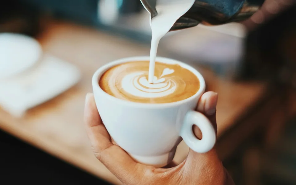 Barista pouring milk to create latte art.