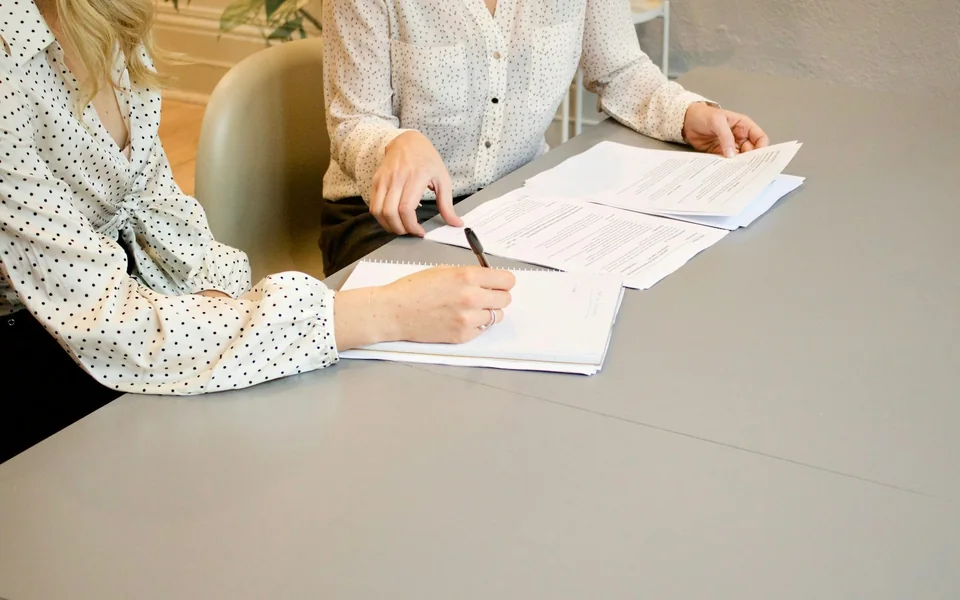 Two professionals reviewing and signing paperwork.